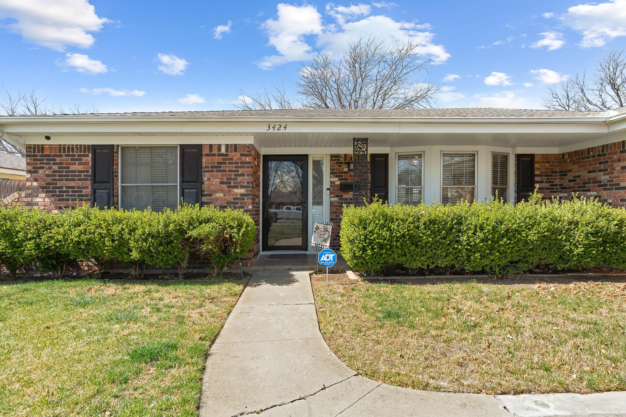 3424 Wayne Street Amarillo, TX 79109 - Photo 1 of 33 a view of a brick house with potted plants and a large tree
