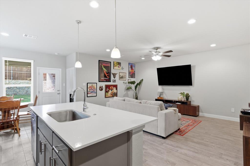 141 Medina Lane Rhome, TX 76078 - Photo 13 of 36 Kitchen island with an undermount sink, quartz countertop, and pendant lighting