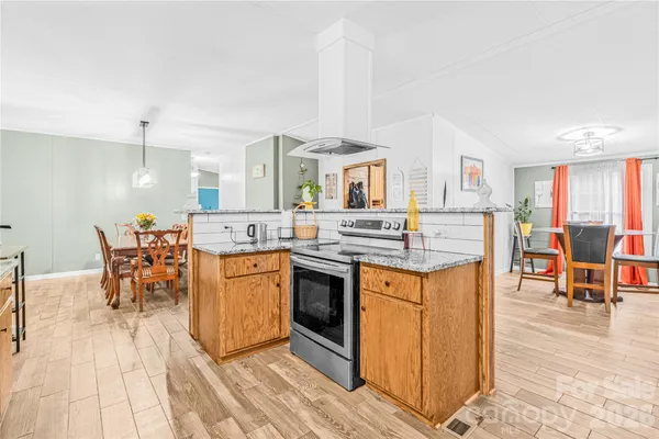 a kitchen with stainless steel appliances granite countertop a stove top oven a sink a dining table and chairs