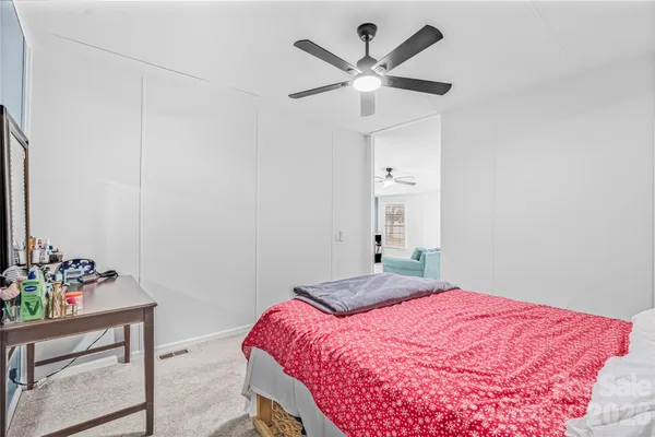 a bedroom with a bed chandelier and a window