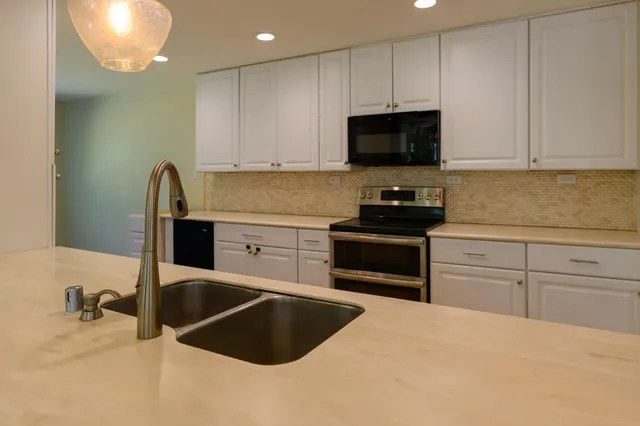 a kitchen with stainless steel appliances granite countertop a stove a sink and a microwave