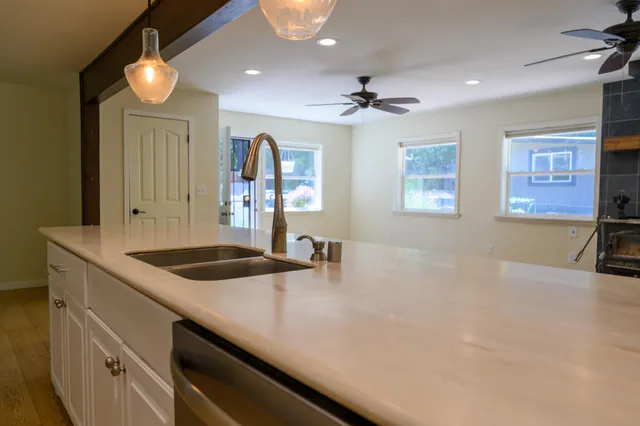 a large open kitchen with stainless steel appliances granite countertop a stove top oven a sink dishwasher and a microwave with wooden floor