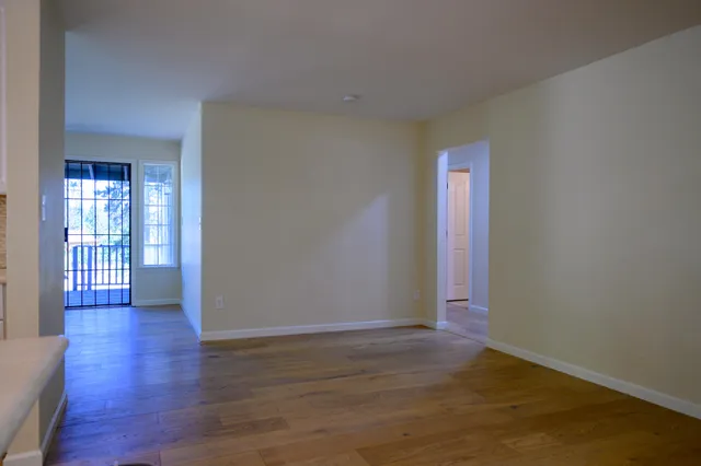 a view of an empty room with wooden floor and a window