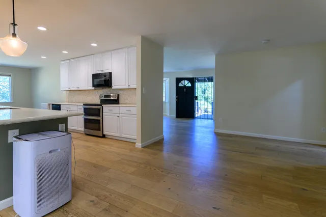 a view of an empty room with wooden floor and a window