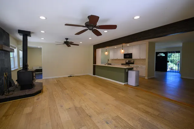 a kitchen with stainless steel appliances kitchen island granite countertop a refrigerator a stove and a sink with wooden floor