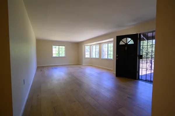 a view of an empty room with a window and a kitchen