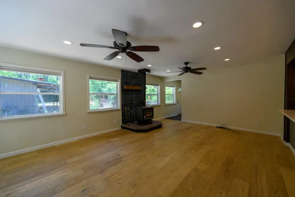 a view of an empty room with wooden floor and a window