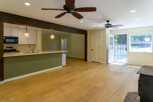 a view of empty room with wooden floor and fan