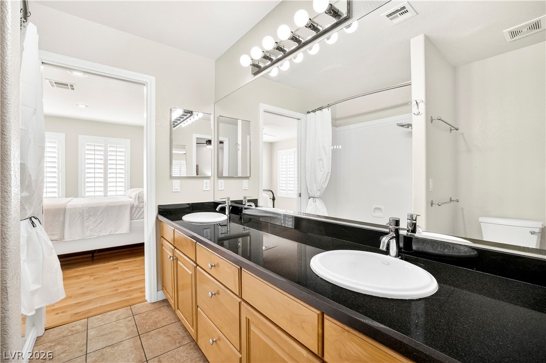 1135 Calico Ridge Drive Henderson, NV 89011 - Photo 40 of 86 Double vanities with sleek countertops complement a well-appointed bathroom leading into a bright bedroom.