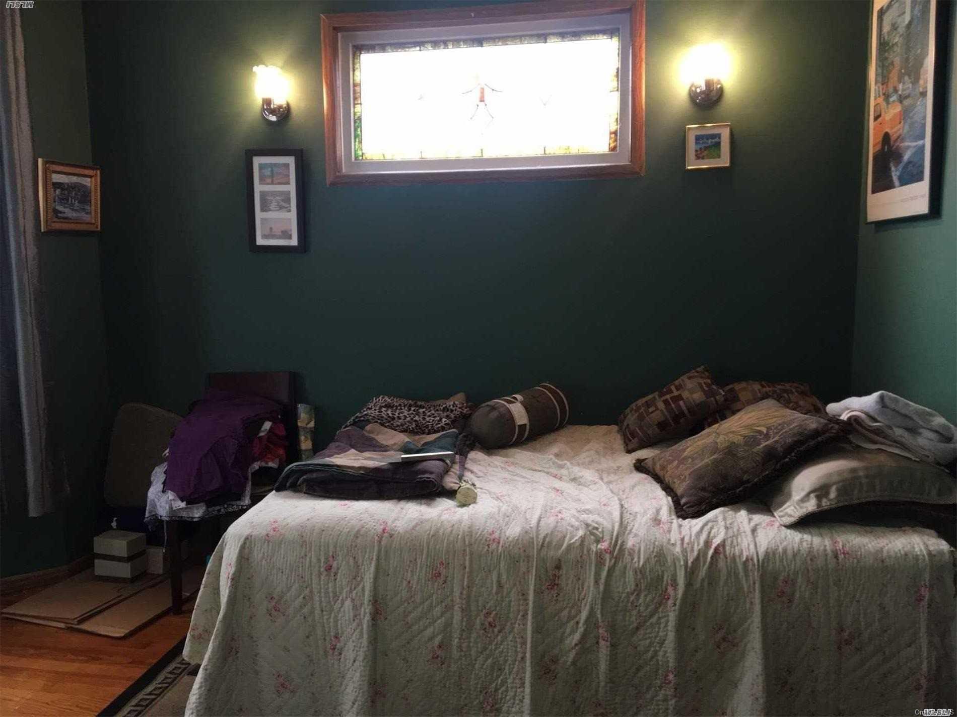 60-13 59th Road Queens, NY 11378 - Photo 16 of 20 a bed sitting in a bedroom next to a window