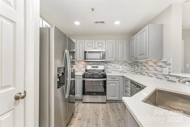 a kitchen with a sink cabinets stainless steel appliances and a window