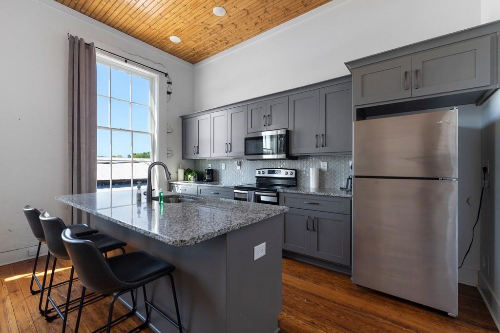 a kitchen with stainless steel appliances granite countertop a refrigerator a sink a stove a dining table and chairs