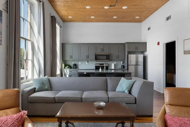 a living room with a couches and kitchen view with wooden floor