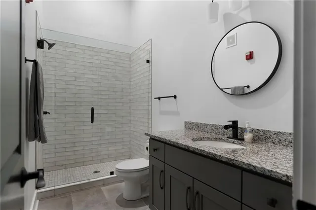 a bathroom with a granite countertop toilet sink and mirror