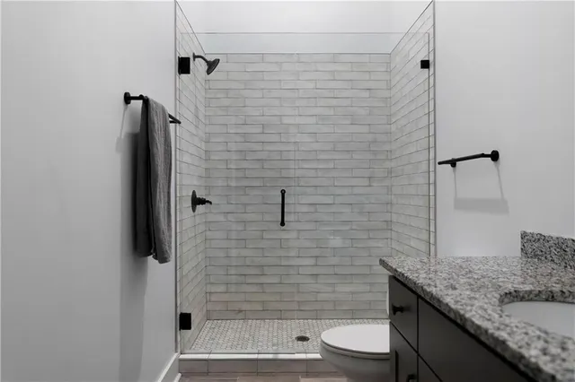 a bathroom with a granite countertop toilet a sink and shower