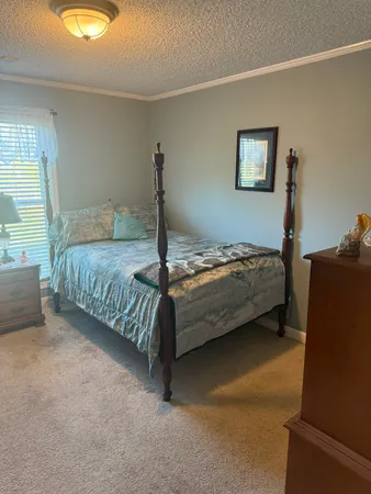 a bedroom with a bed and a lamp on dresser