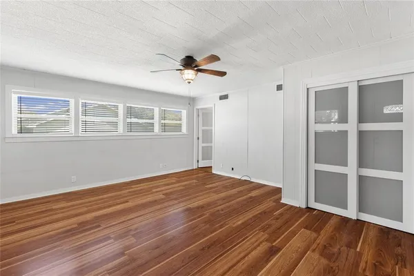 a view of empty room with wooden floor and fan