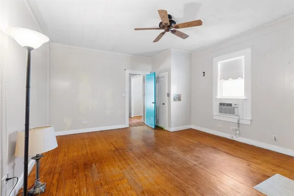 a view of empty room with wooden floor and fan
