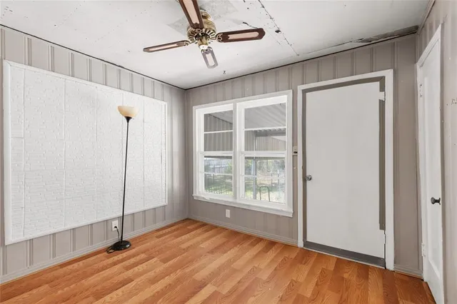 a view of empty room with wooden floor and fan