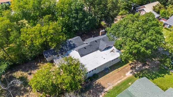 an aerial view of a house with a yard and covered with trees