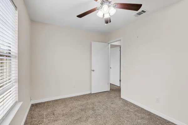 an empty room with a chandelier fan and windows