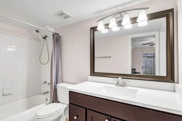 a bathroom with a granite countertop sink toilet mirror and a bathtub