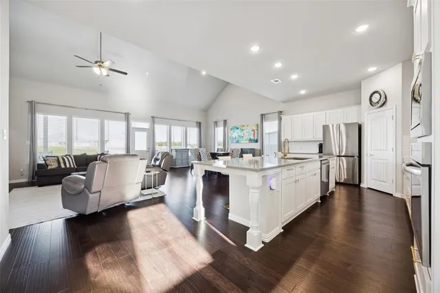 a large white kitchen with lots of counter space a sink and stainless steel appliances