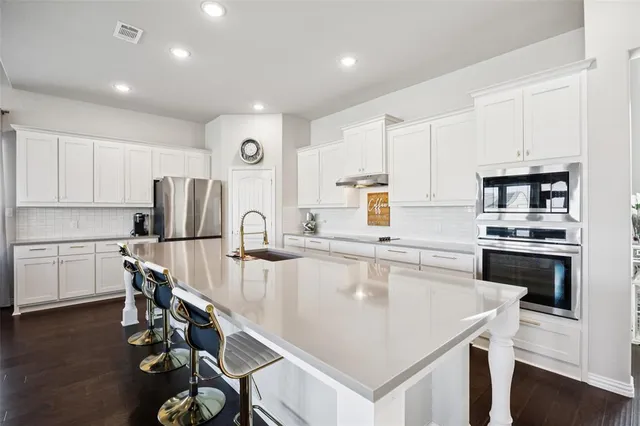 a kitchen with kitchen island a white counter top space cabinets and stainless steel appliances