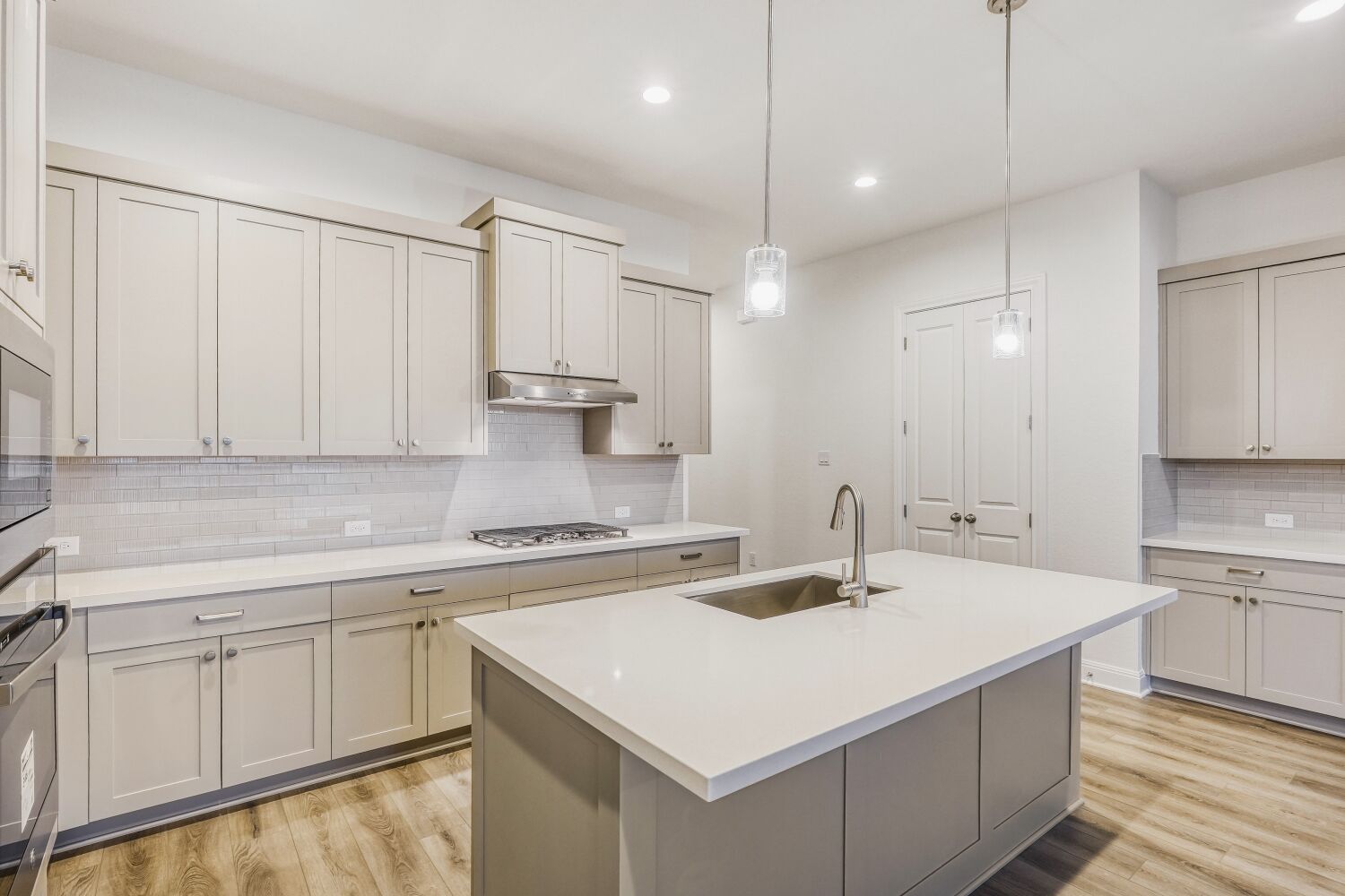 222 Prickly Poppy Loop Kyle, TX 78640 - Photo 4 of 11 a kitchen with a sink dishwasher and white cabinets with wooden floor
