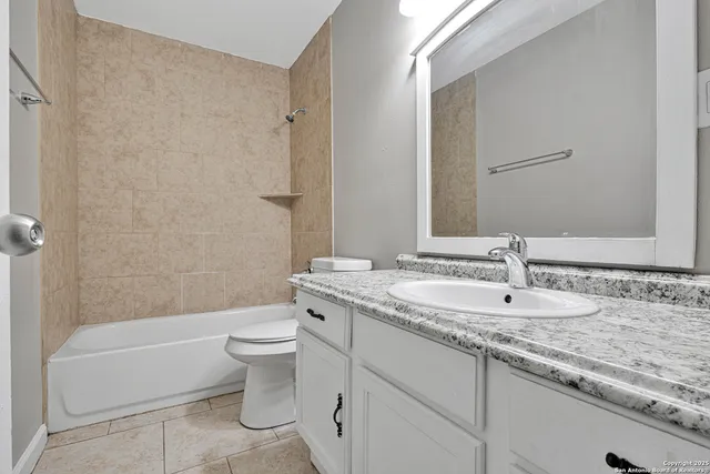 a bathroom with a granite countertop toilet a sink and a bathtub