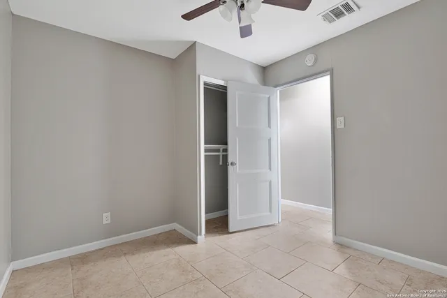an empty room with closet and a chandelier fan