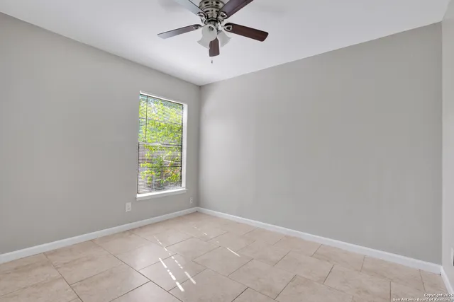 an empty room with windows and fan