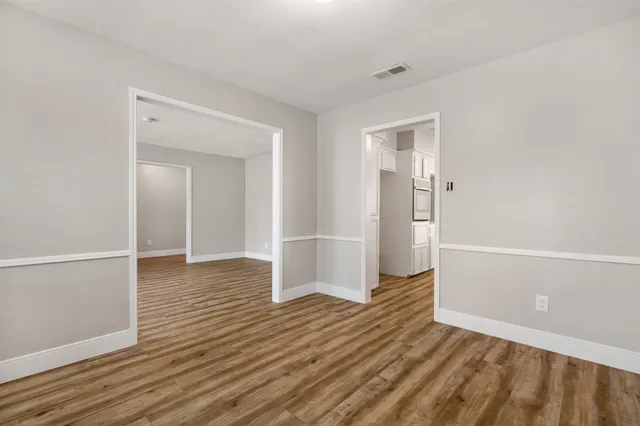 a view of an empty room with wooden floor fireplace and a window