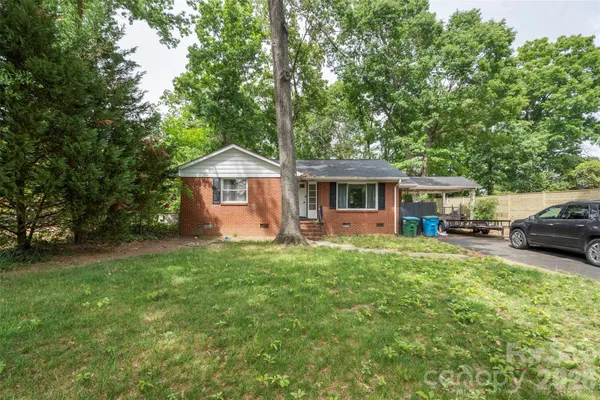 a view of a house with a big yard and large trees