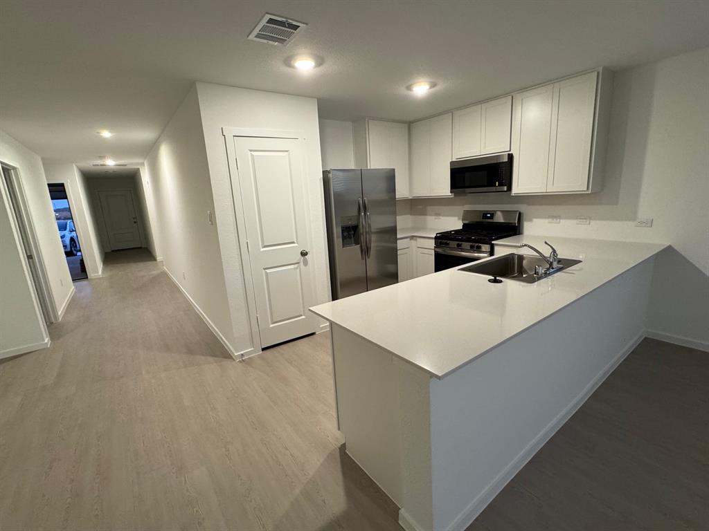 7809 Bent Gale Road Pilot Point, TX 76258 - Photo 17 of 17 a kitchen with white cabinets and stainless steel appliances