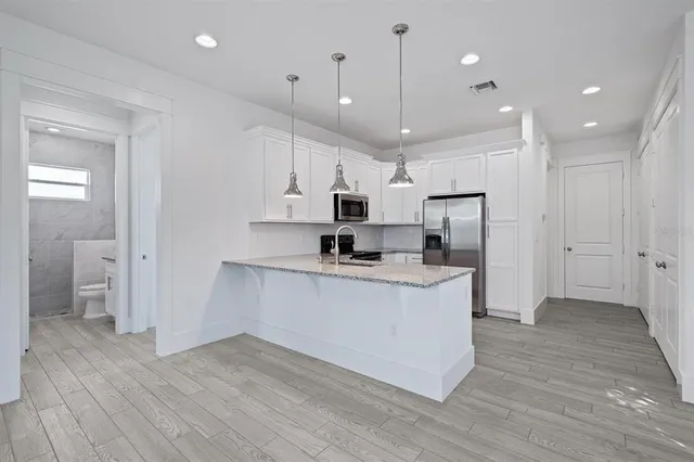 a large kitchen with stainless steel appliances granite countertop a large counter top a sink and a refrigerator