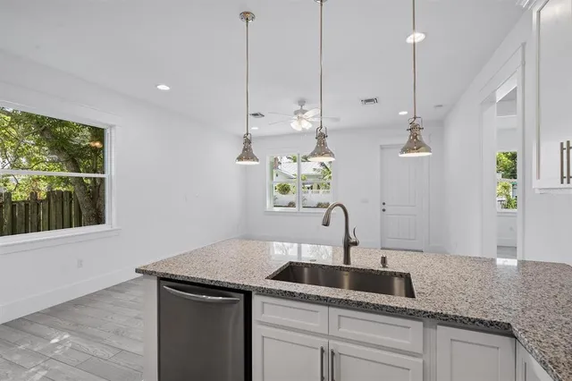 a kitchen with a sink a counter top space and living room view