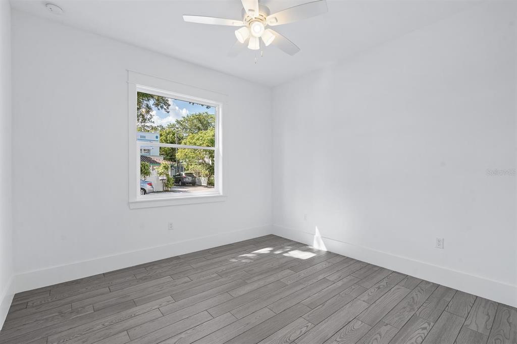 667 Southwest Cleveland Avenue, Unit 2 Stuart, FL 34994 - Photo 6 of 10 an empty room with wooden floor chandelier fan and windows