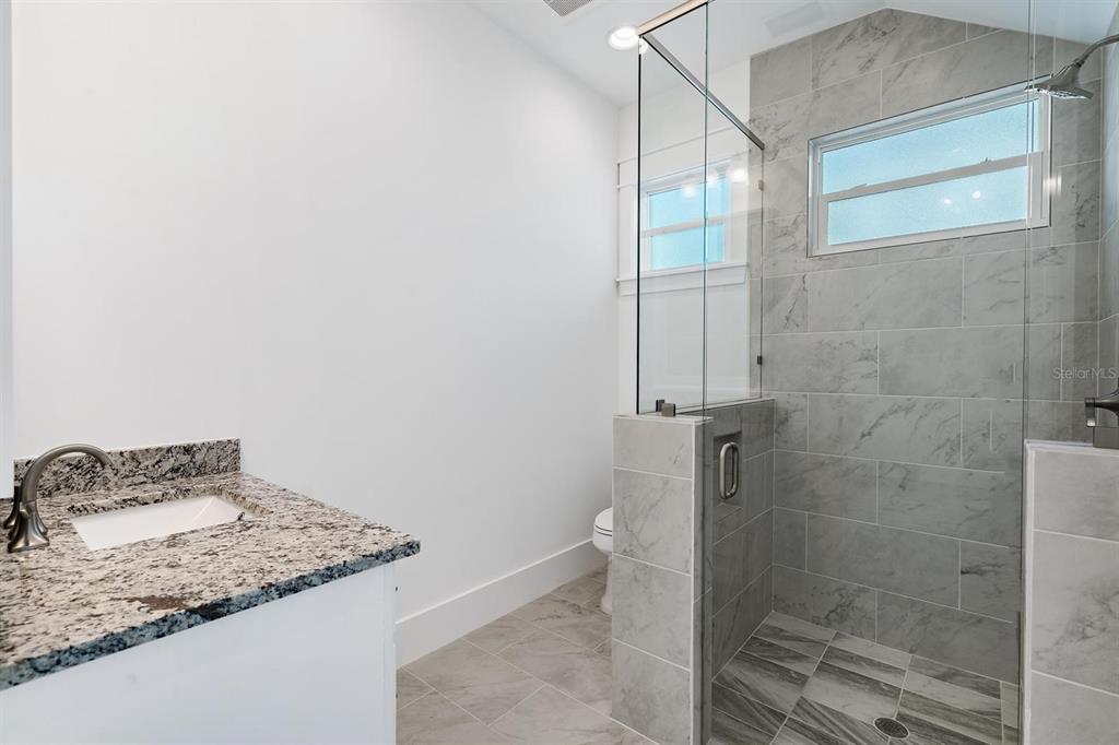 667 Southwest Cleveland Avenue, Unit 2 Stuart, FL 34994 - Photo 7 of 10 a bathroom with a granite countertop sink and a mirror