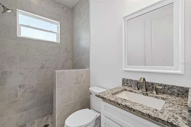 a bathroom with a granite countertop toilet sink and mirror