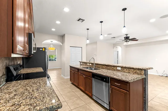 a kitchen with stainless steel appliances granite countertop a sink a stove and a wooden floors