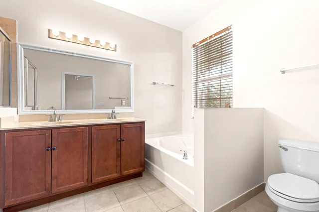 a bathroom with a bathtub shower sink vanity mirror and toilet