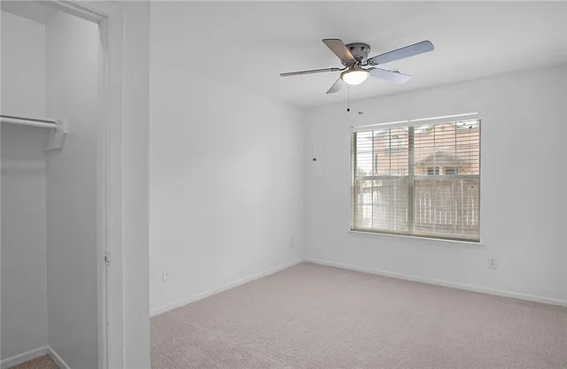 an empty room with window and ceiling fan