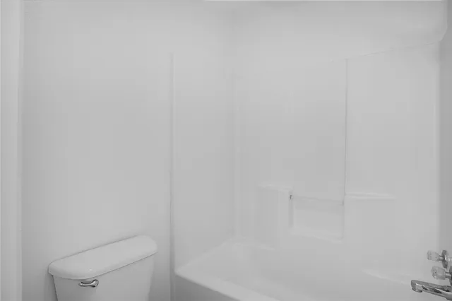 a white toilet sitting next to a shower