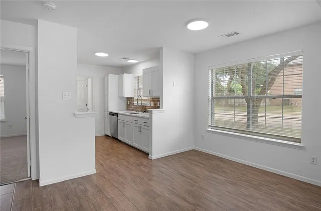 a kitchen with stainless steel appliances wooden floors and white cabinets