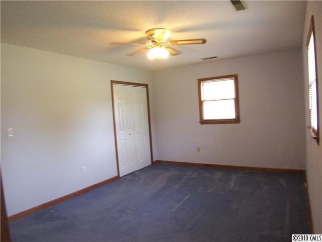 409 Robinson Creek Road Bostic, NC 28018 - Photo 5 of 9 an empty room with a chandelier fan and windows