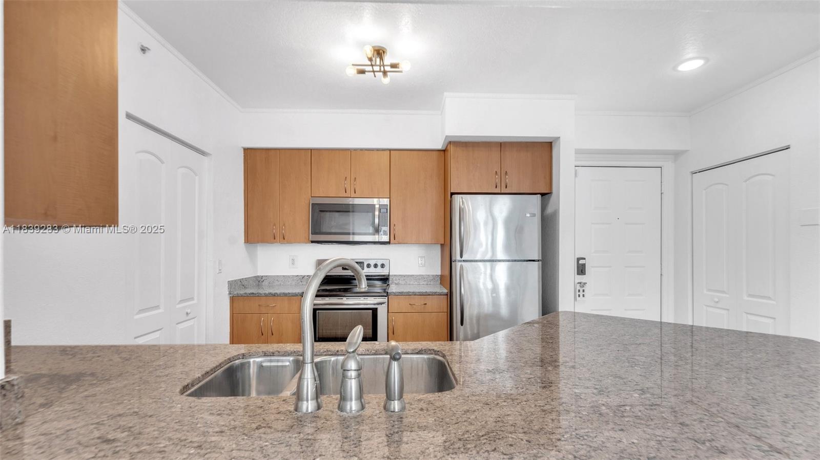 1830 Radius Drive, Unit 405 Hollywood, FL 33020 - Photo 12 of 28 a kitchen with stainless steel appliances granite countertop a refrigerator a stove a sink a microwave a dining table and chairs with wooden floor