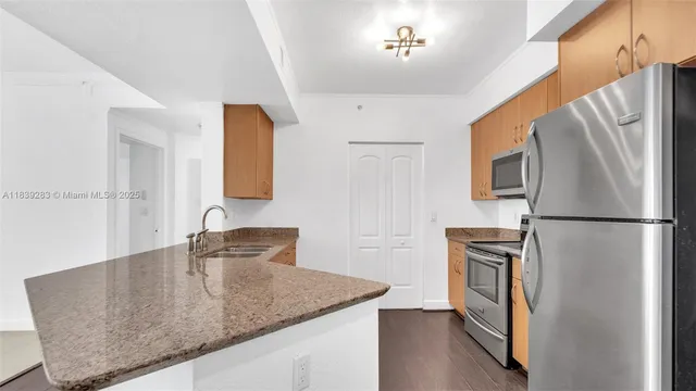 a kitchen with stainless steel appliances granite countertop a refrigerator a sink and a stove