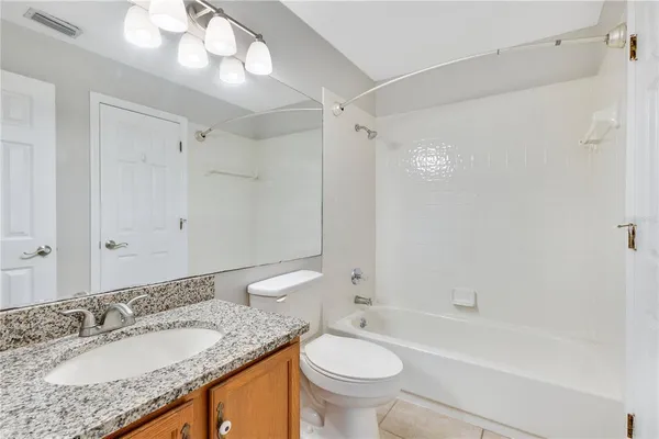 a bathroom with a granite countertop sink toilet mirror and bathtub