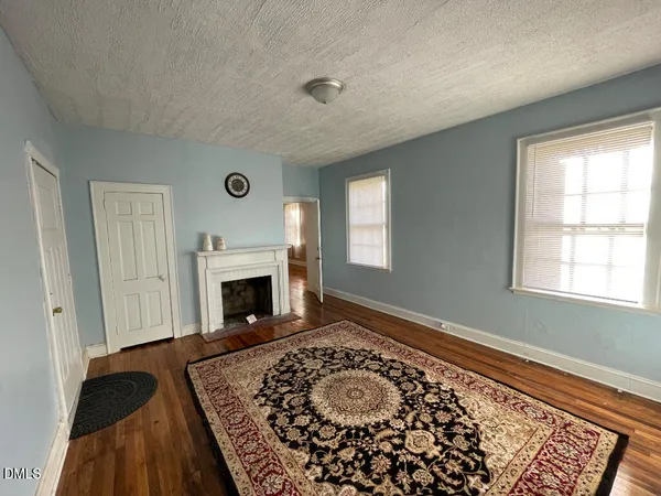 a view of a livingroom with a fireplace window and wooden floor